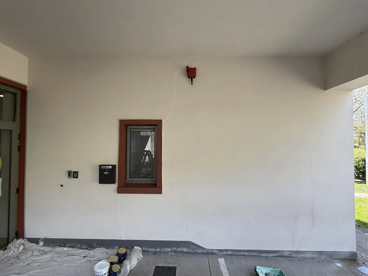 A blank cream school entrance wall before painting, with dust sheets and paint tins on the ground