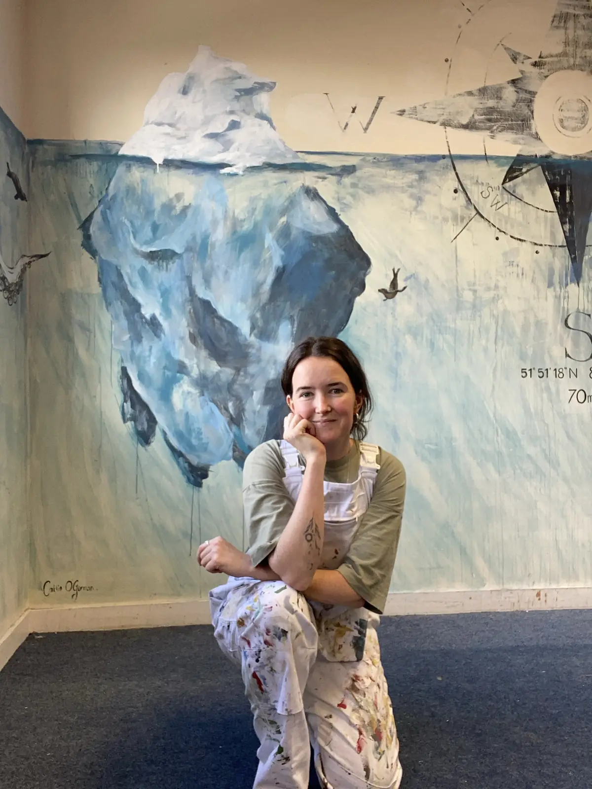 Caitlin in front of her painted iceberg wall, its mass carrying on below the waterline